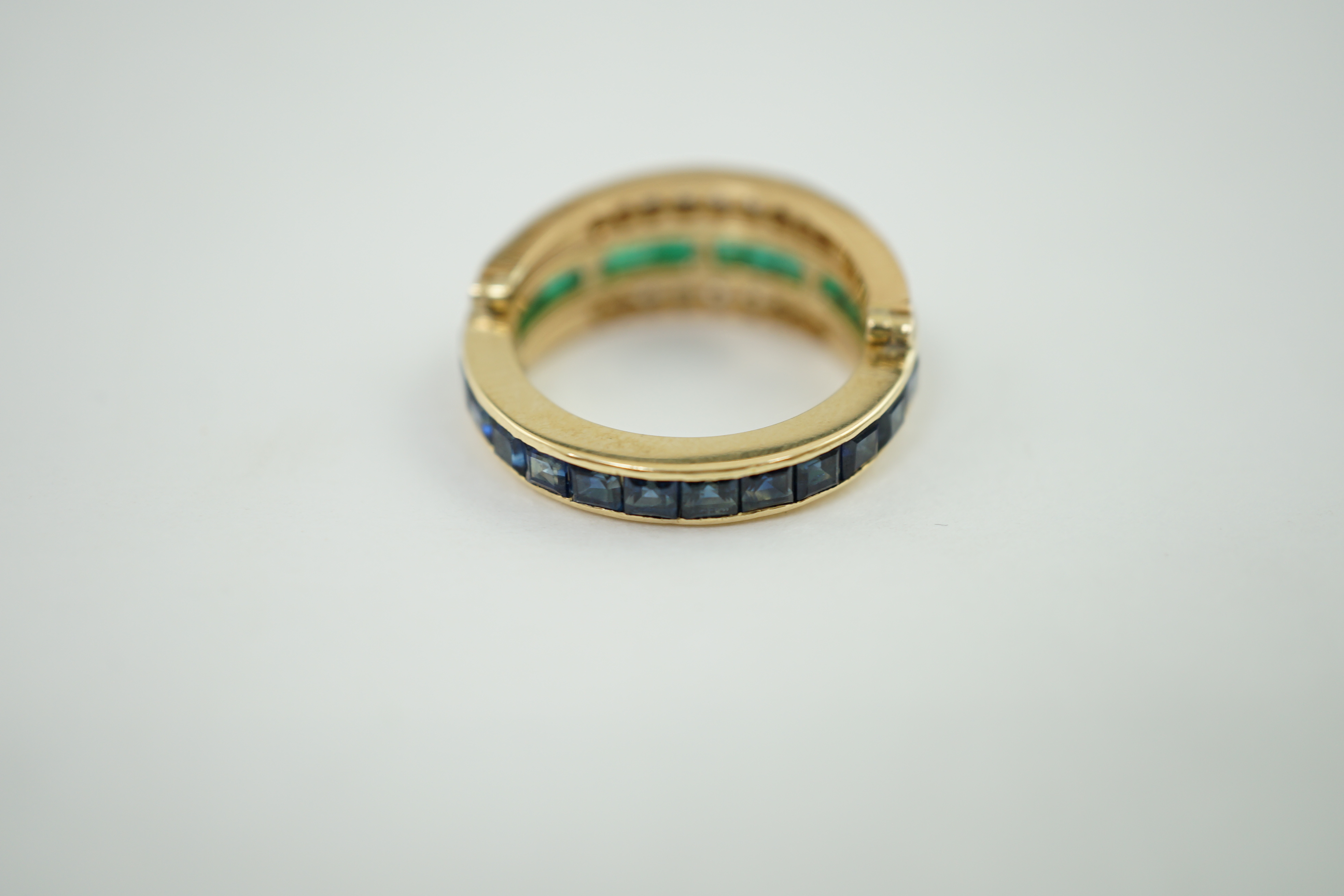 A recent gold, emerald, sapphire and diamond set triple band swivelling eternity ring